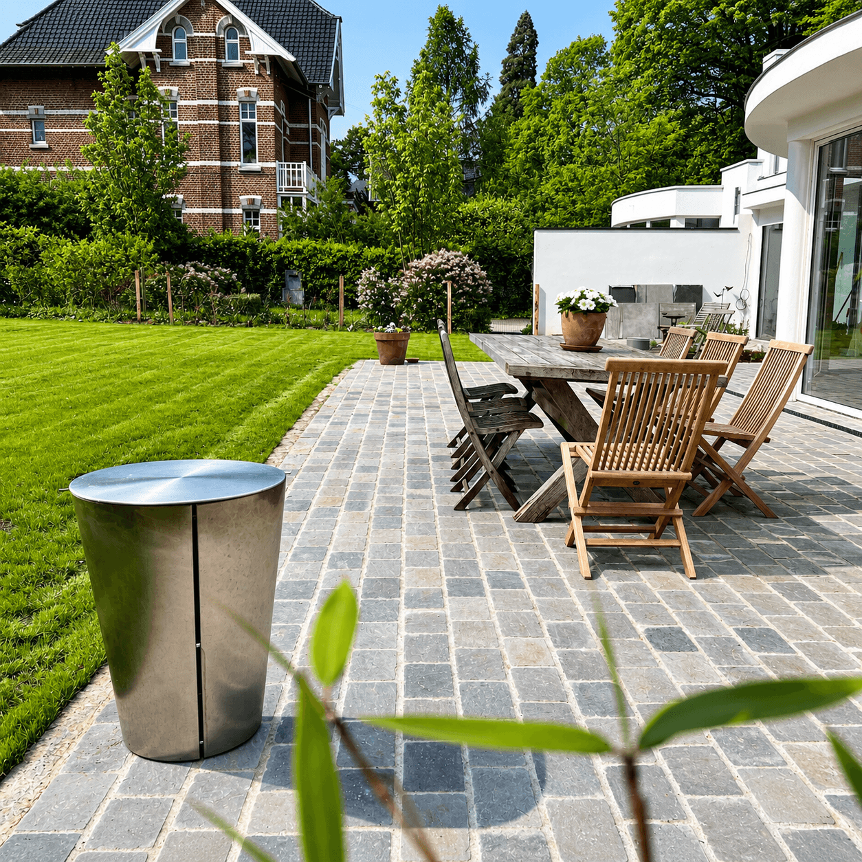 Terrasse pavée avec table de jardin, en bordure de pelouse